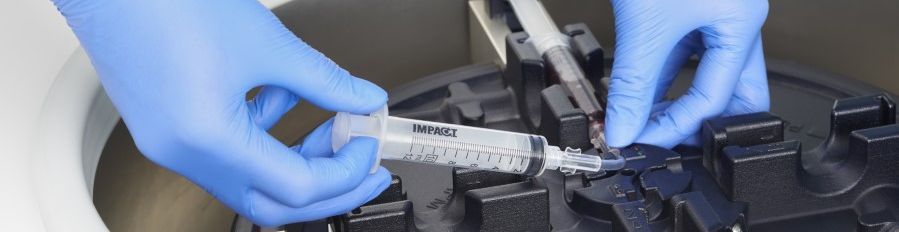 Eine Spritze mit Eigenblut wird in die Halterung der Zentrifuge eingelegt