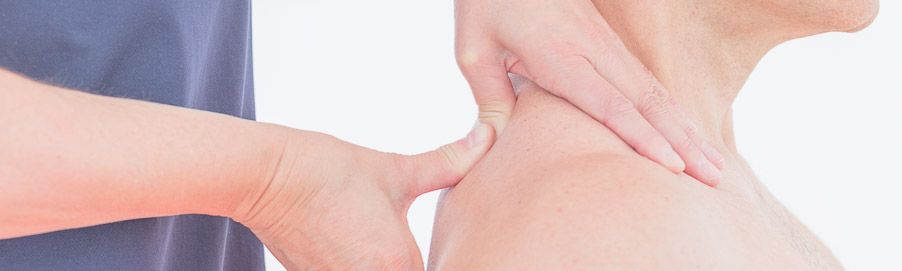 Manualtherapeutische Behandlung: die Ärztin tastet mit beiden Händen Nacken und Schulter einer Patientin ab